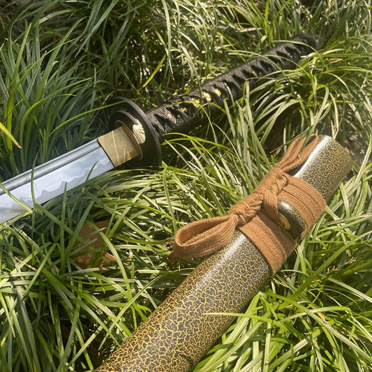 The Forest Viper Katana, featuring a 1095 steel blade and a green snake-pattern saya, crossed in an outdoor setting.