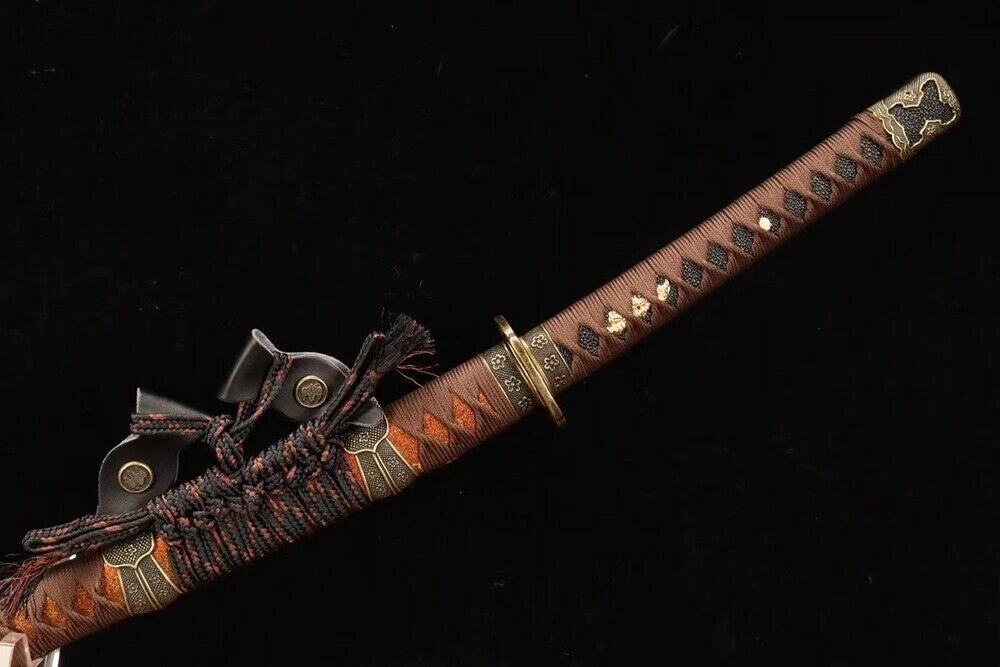 A close-up of the tsuka handle, featuring the dark brown silk ito wrap and antique-finish copper tsuba.