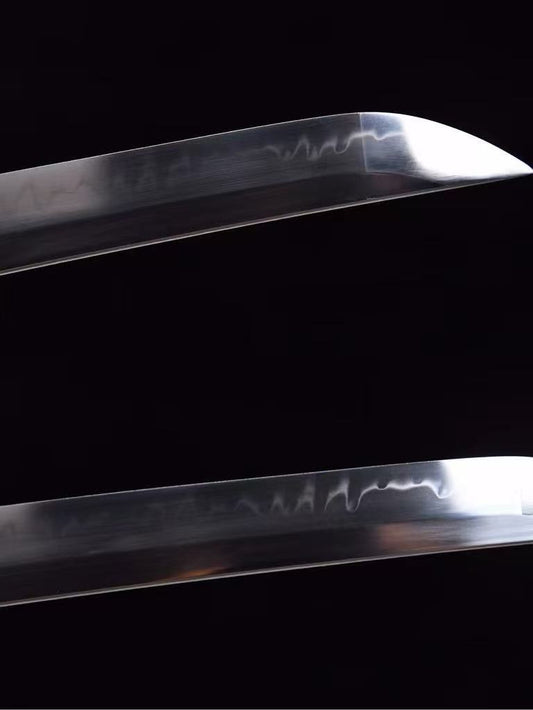 A close-up of the T10 steel blade of the Orochi's Coil Katana, showing the authentic clay-tempered hamon line.