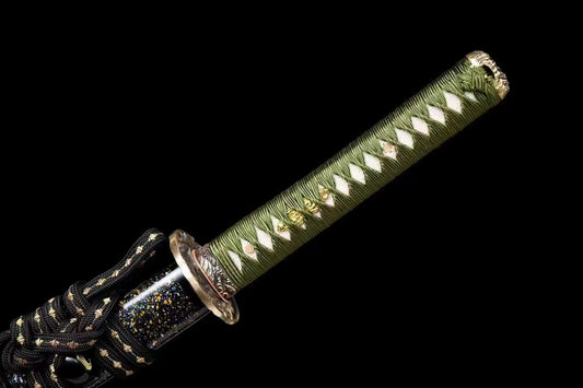 A close-up of the tsuka handle, featuring green silk ito wrap and brass fittings with an eagle theme.