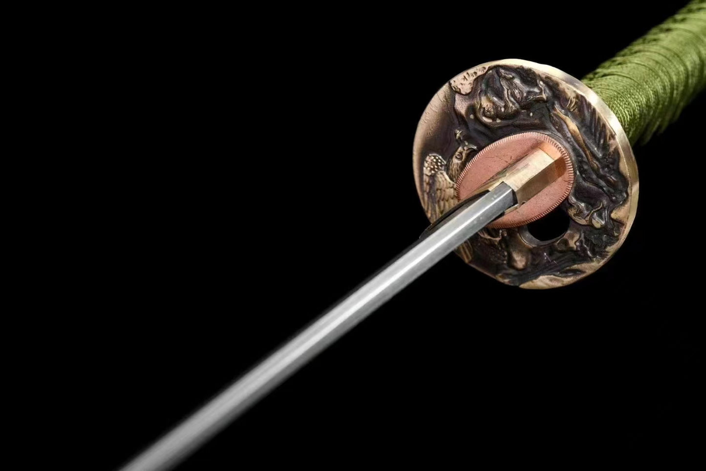 A macro view of the brass tsuba, featuring an intricate eagle theme, on the Celestial Eagle Katana.