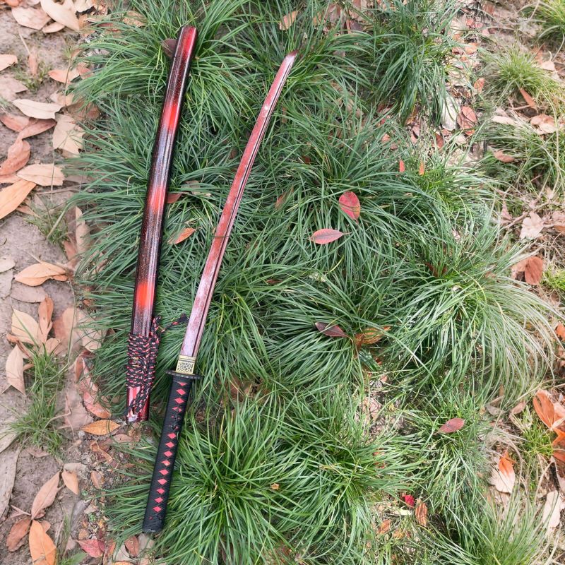 An angled, full-length view of the unsheathed Inferno Blade Katana and its saya.