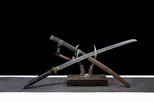 The Bridlewood Tachi with its folded steel blade crossed over the Huali wood saya on a display stand.