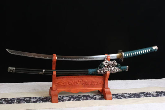 The Verdant Trace Tachi, featuring a folded steel clay-tempered blade and ornate fittings, on a display stand.