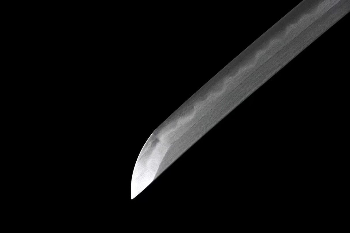 A detailed shot of the sharp chu-kissaki tip of the Honsanmai laminated, folded steel blade.