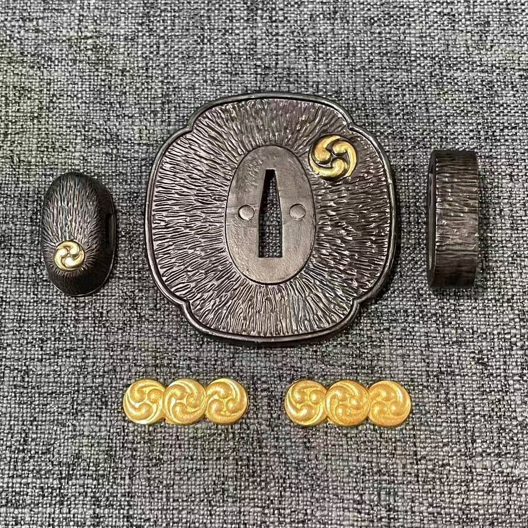 Complete Koshirae set featuring the gilded Mitsu Tomoe symbol on a textured, dark-patinated brass Tsuba, Fuchi, Kashira, and Menuki.