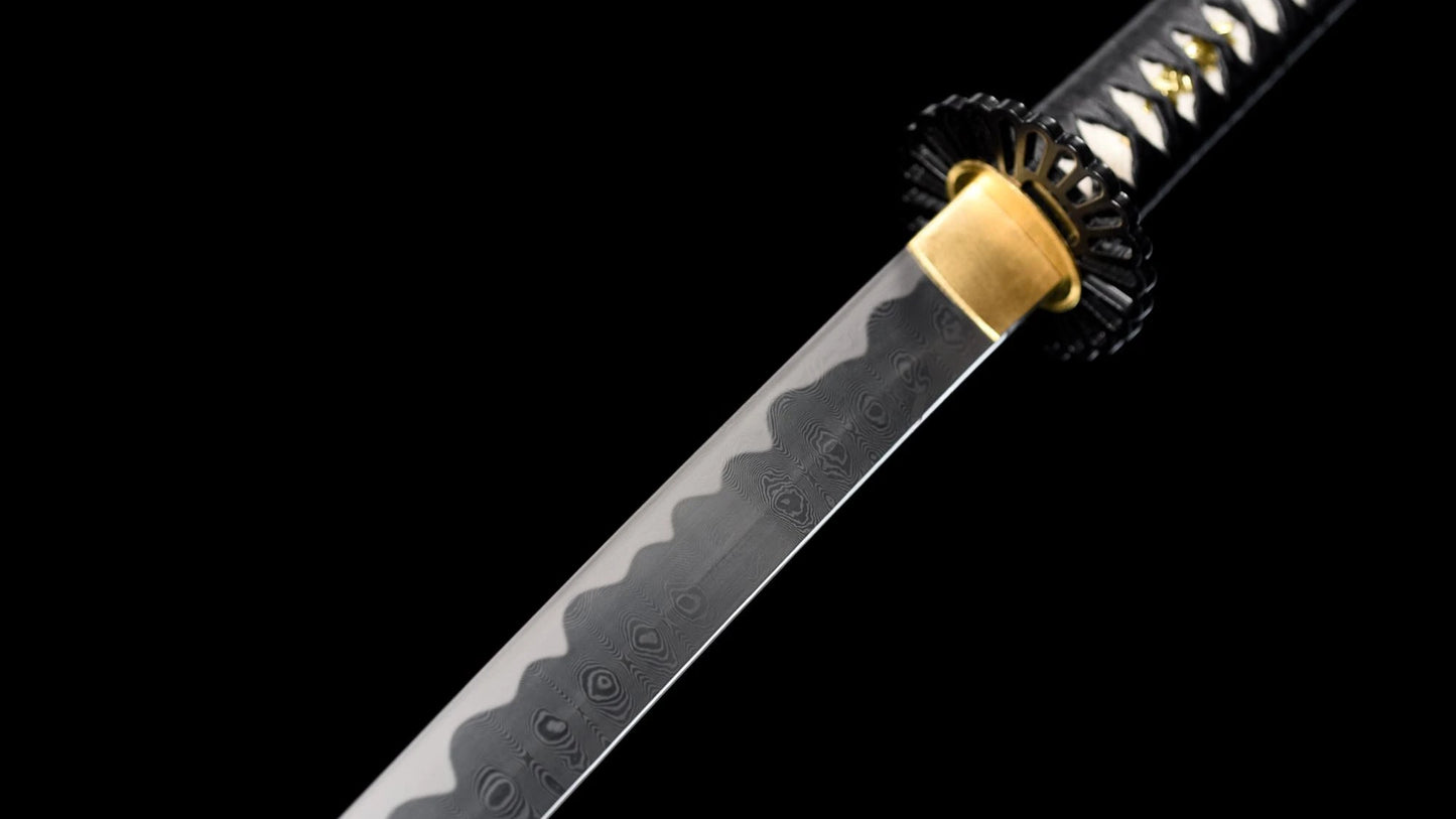 Folded 1095 steel nodachi blade showing the wood-grain hada and notare hamon, with brass habaki and black iron tsuba.