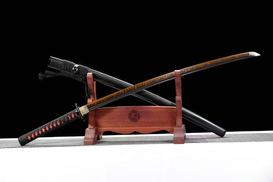The Hinokami "Demon Slayer" katana with its red hamon on a blackened blade, crossed over its speckled saya.