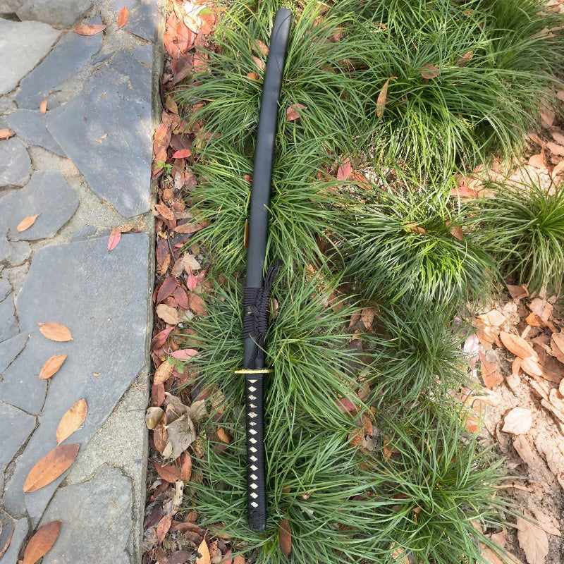 The complete Silent Vein Katana, fully sheathed in its matte black saya, resting in a natural, grassy environment.