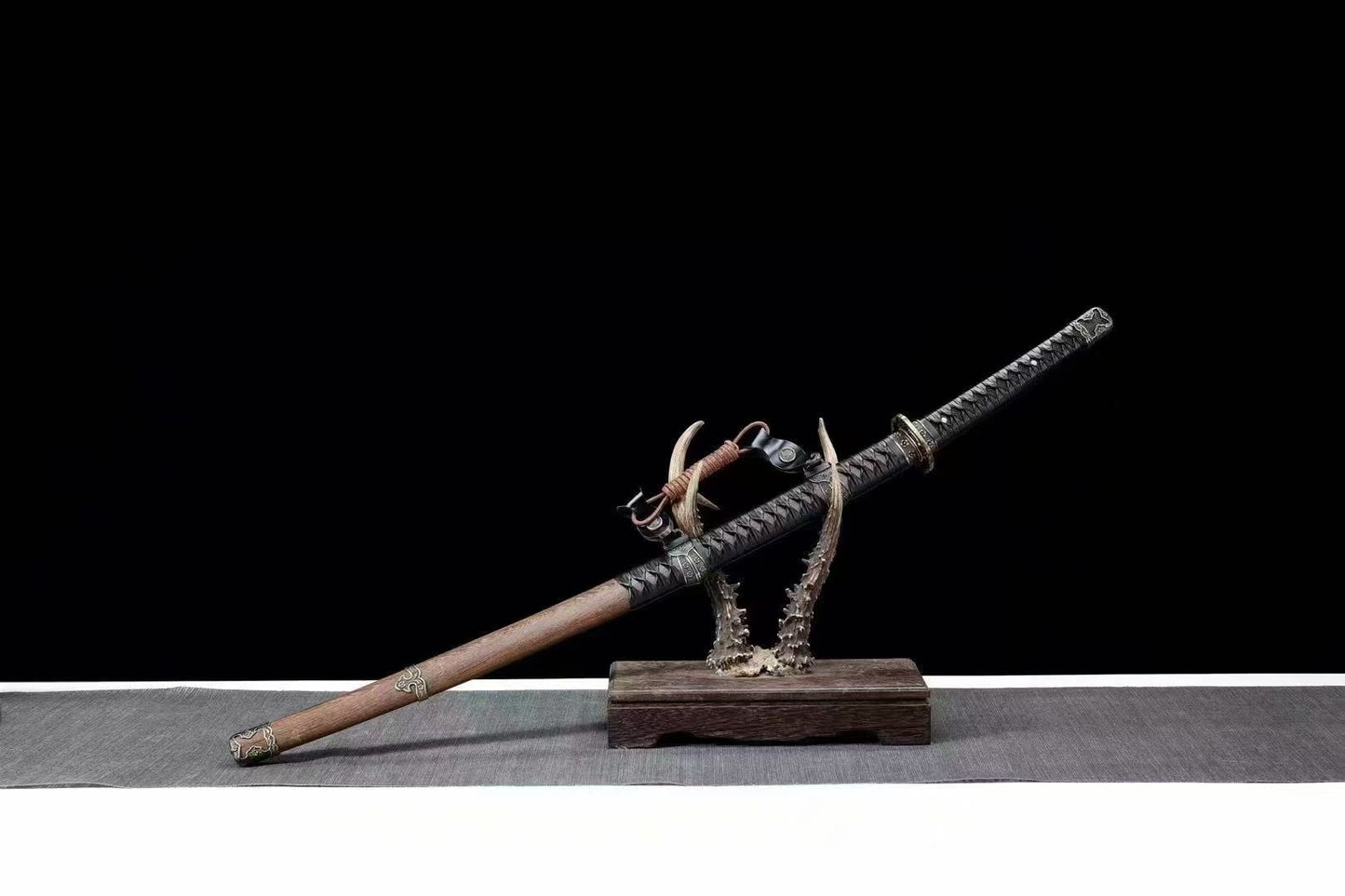 The complete Bridlewood Tachi, fully sheathed in its rosewood saya, resting on a display stand.