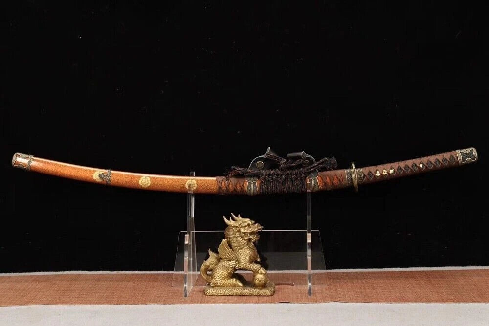 The sheathed Shogun's Golden Tachi displayed on a stand next to a small golden ornament.