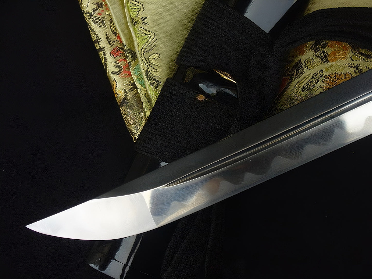 A sharp close-up of the chu-kissaki tip of The Sage's Journey's through-hardened 1095 steel blade.