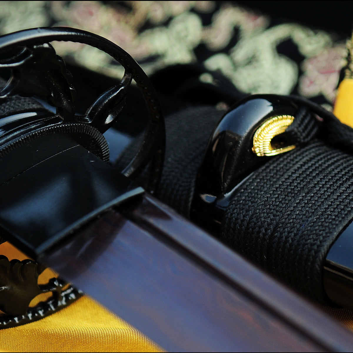 A detailed close-up of the Kuro Akane Katana's saya, featuring the premium black brocade silk sageo tied on the gloss-black lacquer scabbard.