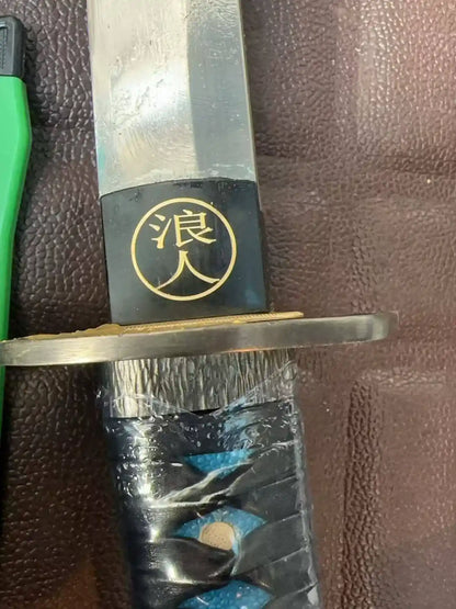 Blackened habaki engraved with a gold 浪人 (rōnin) emblem at the blade collar — close-up
