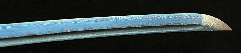 A close-up of the blade, showcasing the unique blue and red pattern of the 8192-layer Damascus folded steel.