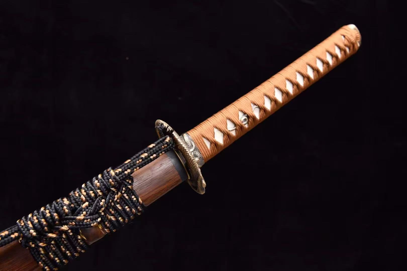 A detailed shot of the brass serpent tsuba and the tsuka handle of the Orochi's Coil Katana.