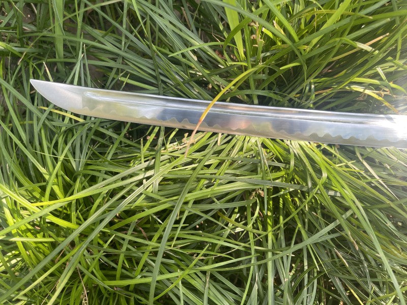 A close-up of the 1095 high-carbon steel blade, showing the real clay-tempered hamon line.
