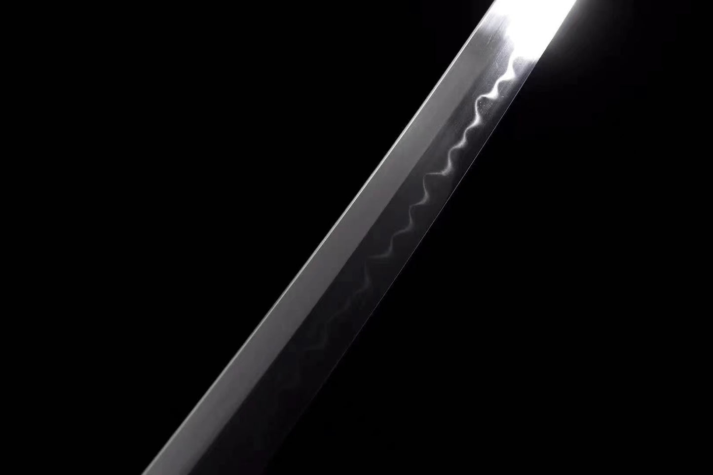 A detailed close-up of the T10 steel blade, clearly showing the authentic and active clay-tempered hamon line.