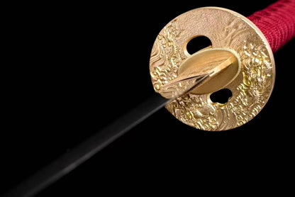 A close-up of the ornate, solid copper tsuba (guard) of the Crimson Hitatsura Katana.