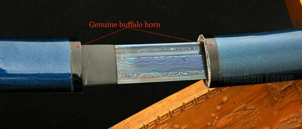 The Blue Damascus folded steel blade emerging from the saya, which features a genuine buffalo horn koiguchi.