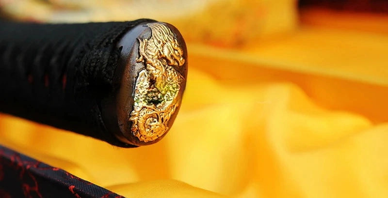 A detailed view of the brass kashira (pommel) at the end of the tsuka, featuring a Dragon (Ryū) theme.