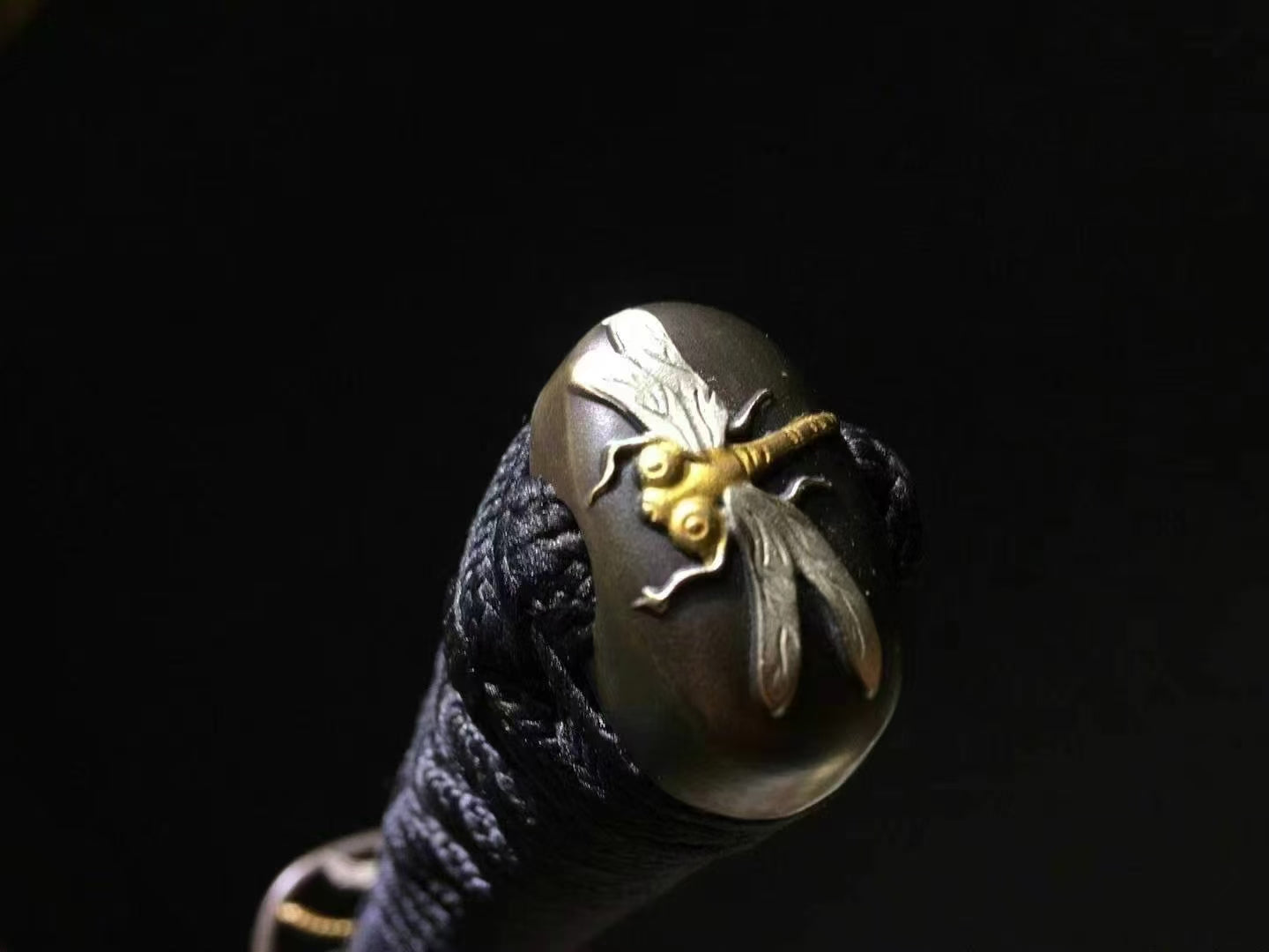 A detailed view of the brass kashira (pommel) at the end of the tsuka, featuring a Dragonfly (Tonbō) theme.