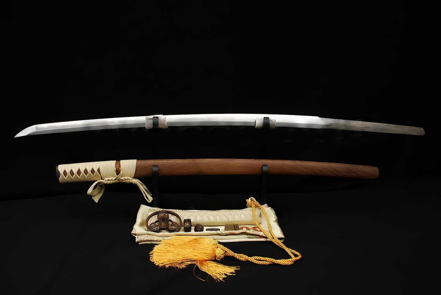 The Gilded Tomoe Katana unsheathed, showing the folded 1095 steel blade with hamon, natural Hualee wood saya, and silk sword bag.