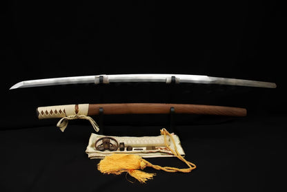 The Gilded Tomoe Katana unsheathed, showing the folded 1095 steel blade with hamon, natural Hualee wood saya, and silk sword bag.