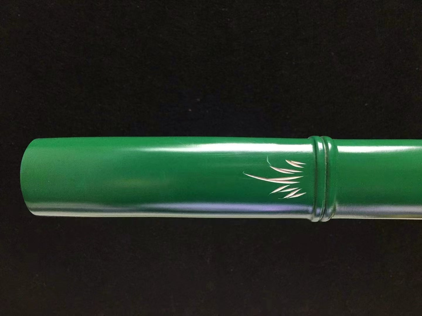 A detailed view of the hardwood tsuka (handle), carved and painted to resemble a green bamboo stalk.