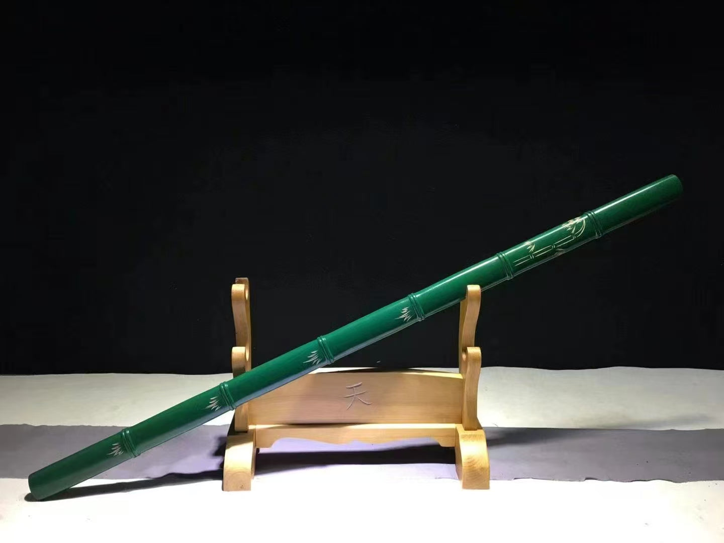 The complete Green Phantom Bamboo Blade, sheathed and resting at an angle on its display stand.