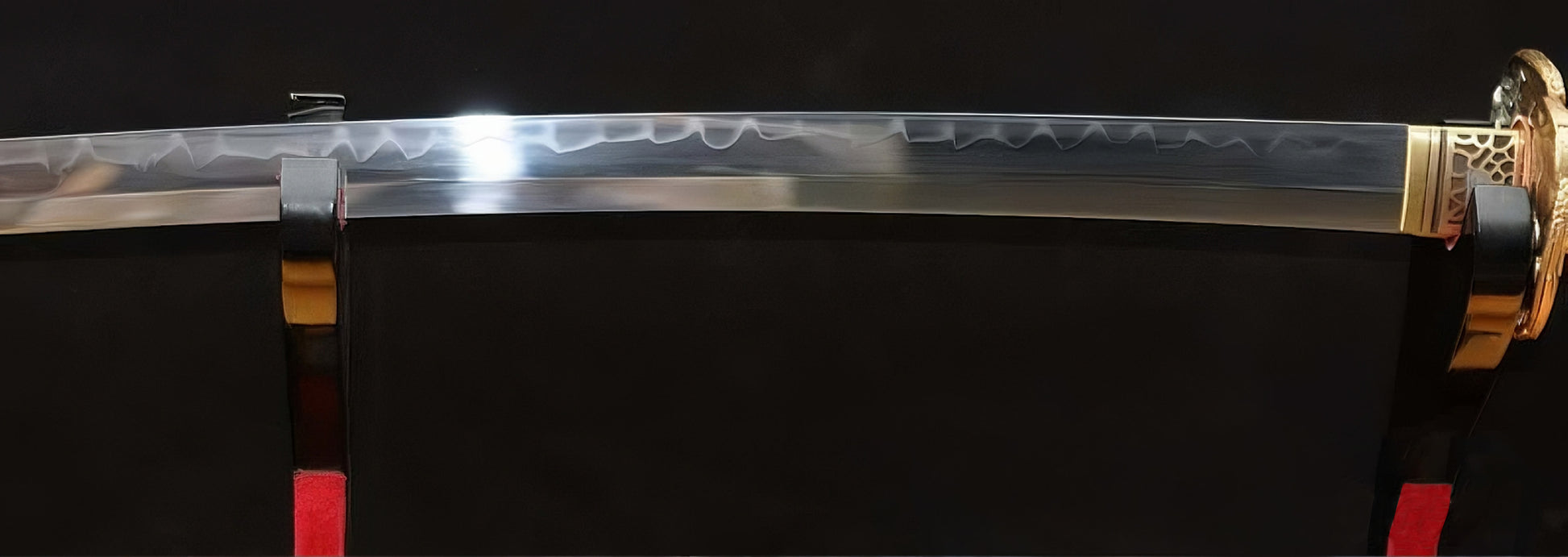 A full-length view of the Golden Hawk Katana's blade on a stand, highlighting the dramatic, misty white Hadori-polished hamon.