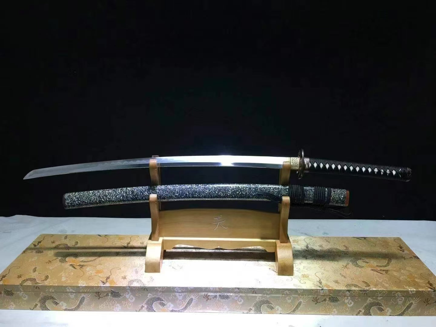 The unsheathed Tonbō Raden Katana on a stand, showing the full Honsanmai folded steel blade and its saya.