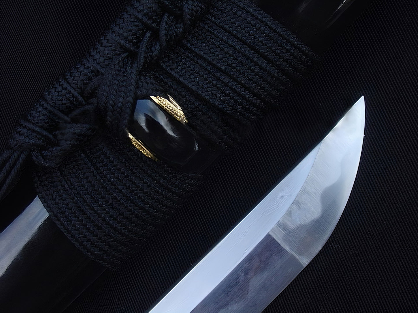 A close-up of the Kiku's Reflection Katana, showing the mirror-polished 1095 steel kissaki (tip) next to the high-gloss black saya.