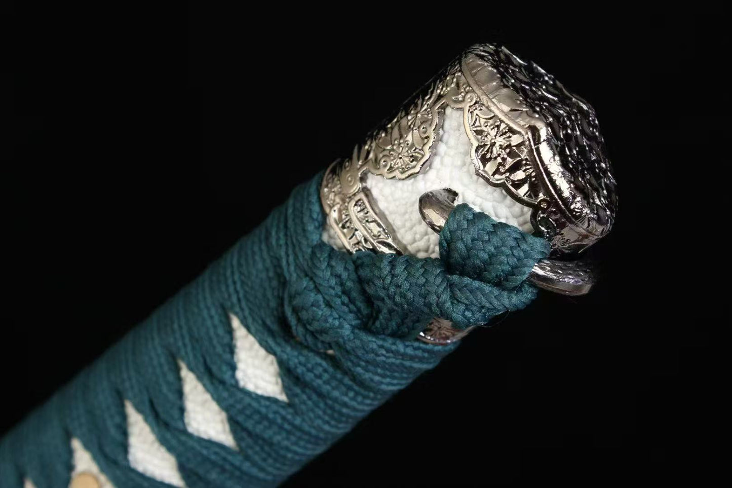 A detailed view of the ornate alloy kashira (pommel) at the end of the Verdant Trace Tachi's handle.