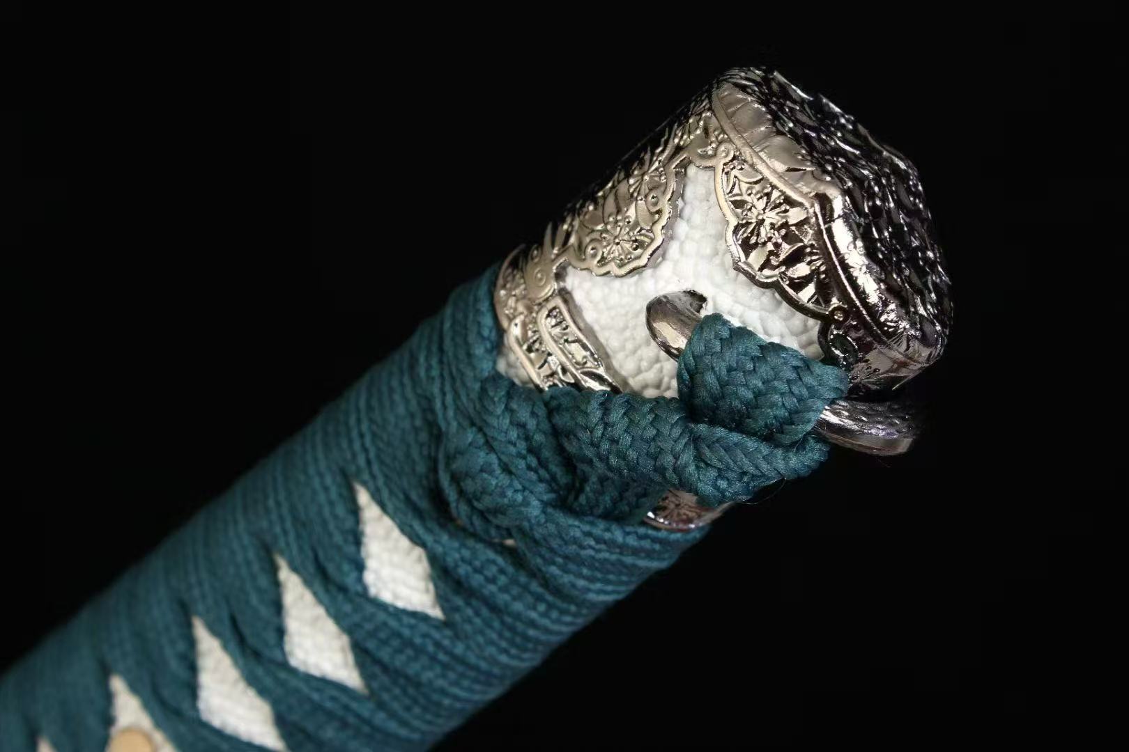 A detailed view of the ornate alloy kashira (pommel) at the end of the Verdant Trace Tachi's handle.