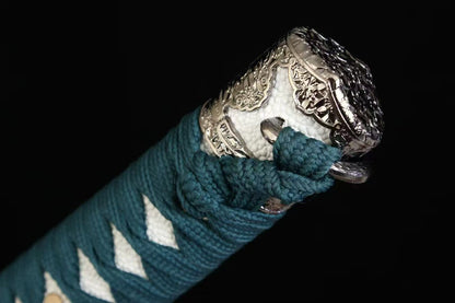 A detailed view of the ornate alloy kashira (pommel) at the end of the Verdant Trace Tachi's handle.