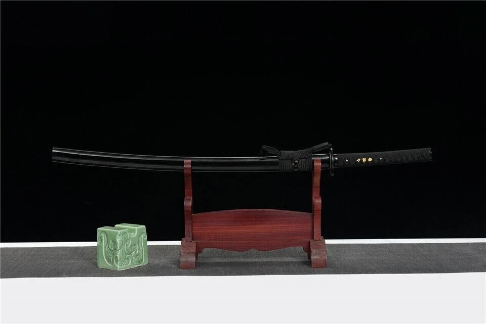 The unsheathed Winter Plum Katana with its folded steel blade and plum blossom tsuba, crossed over the saya.