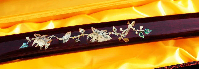 A macro view of the hardwood saya, showcasing the exquisite Raden (mother-of-pearl) bird and flower inlay.