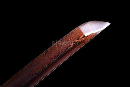 A close-up of the sharp kissaki tip, showcasing the unique red and black pattern of the folded steel blade.