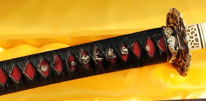 A close-up of the tsuka handle, featuring a black silk ito wrap over striking red genuine rayskin.