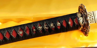 A close-up of the tsuka handle, featuring a black silk ito wrap over striking red genuine rayskin.