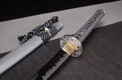 A close-up of the silver alloy tsuba (guard) seated against the matte silver saya.