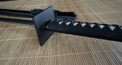 A close-up of the distinctive square iron tsuba and the black silk-wrapped tsuka of the Obsidian Gale.