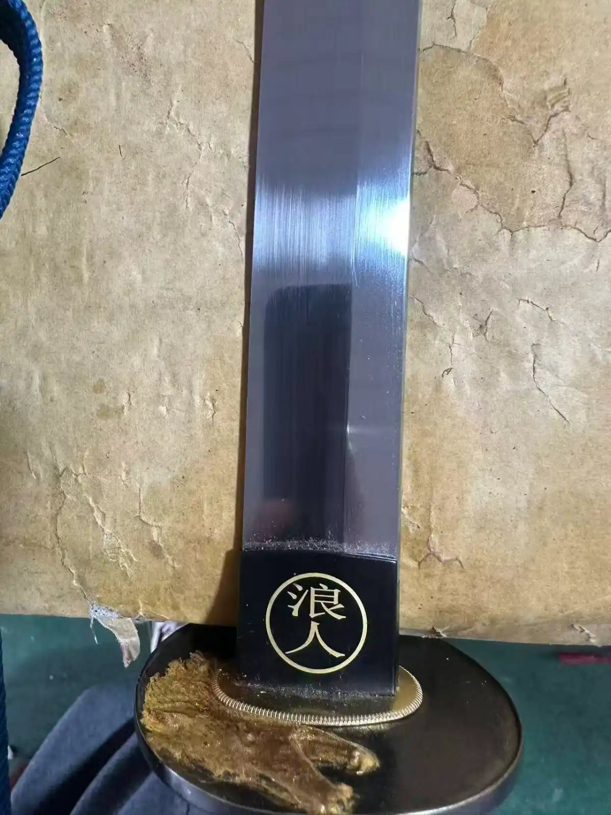 Gold wolf-head tsuba and polished tool-steel blade — close-up