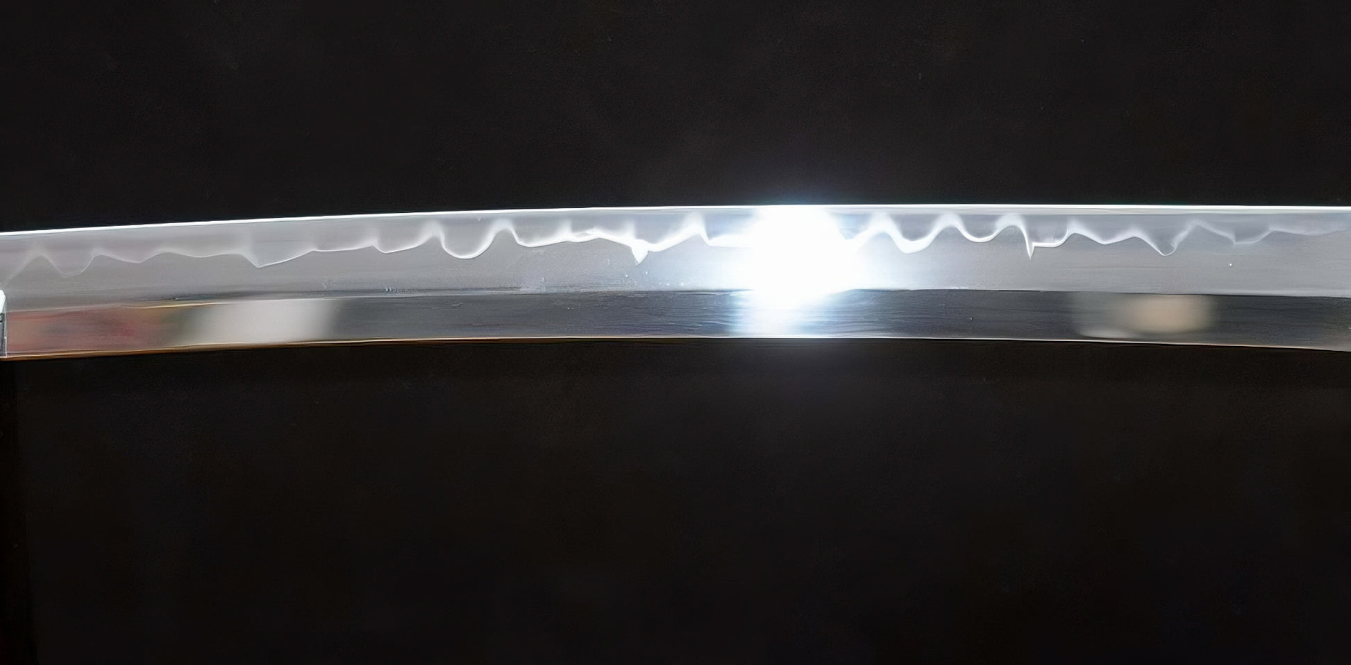 A close-up of the T10 steel blade of the Golden Hawk Katana, showing the authentic clay-tempered hamon which has been enhanced by a traditional Hadori polish.