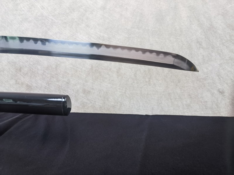 A detailed close-up of the sharp, clay-tempered chu-kissaki tip of the T10 steel blade.