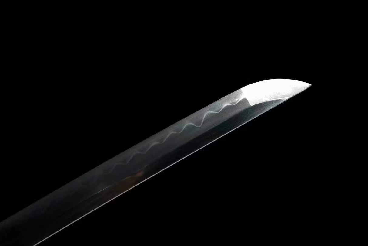 A detailed shot of the sharp chu-kissaki tip of the T10 steel blade, with the hamon visible.