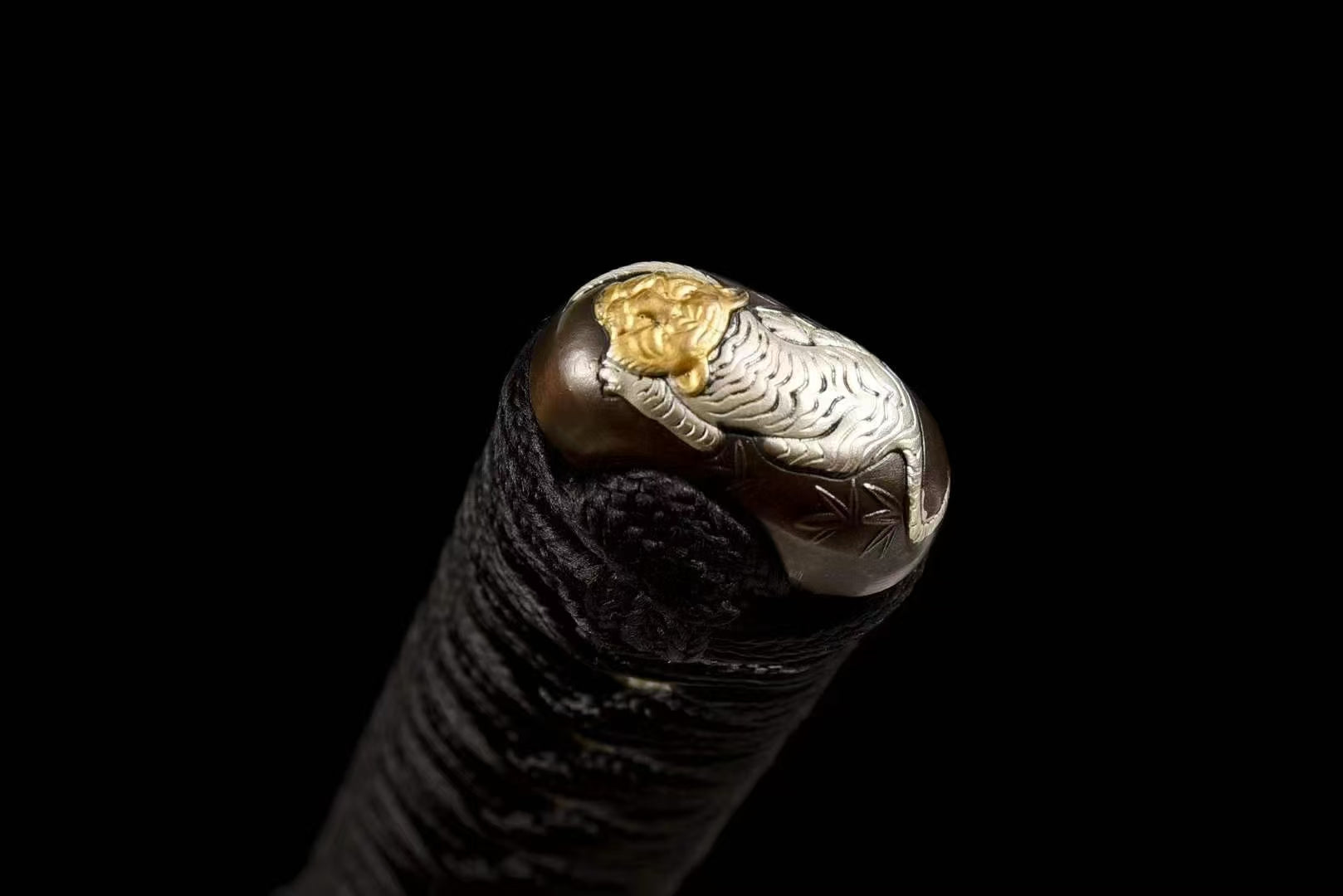 A detailed view of the brass kashira (pommel) at the end of the tsuka, featuring a Tiger (Tora) theme.
