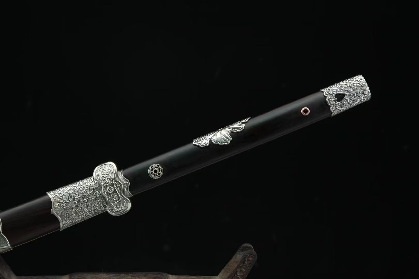 A close-up of the General's Virtue Dao's hilt, showcasing the full ebony handle, white copper guard, and matching fittings on the ebony scabbard.