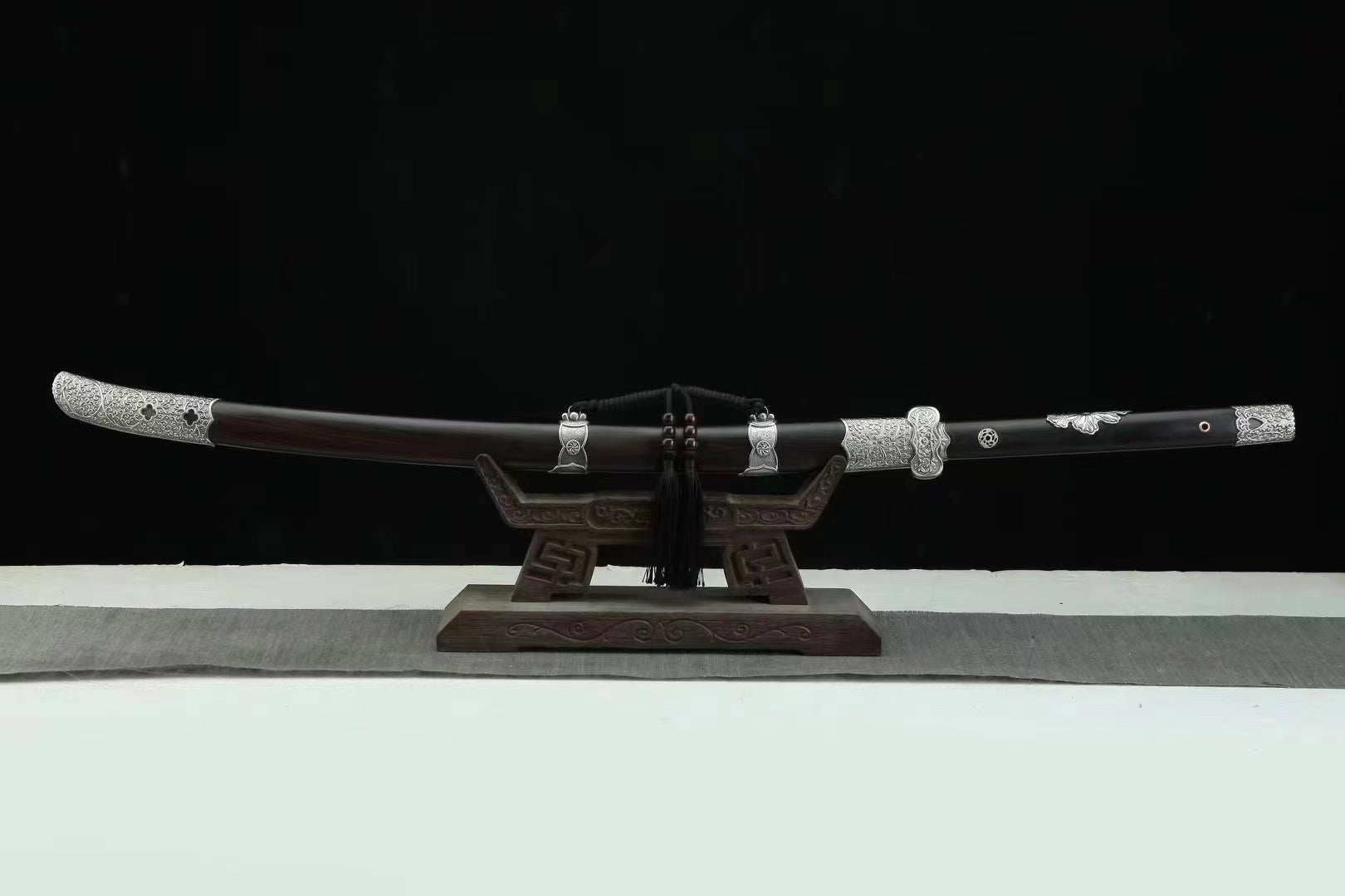 The General's Virtue Dao, showcasing its full length, the complete ebony scabbard, and its intricate white copper (Bai Tong) fittings on a display stand.